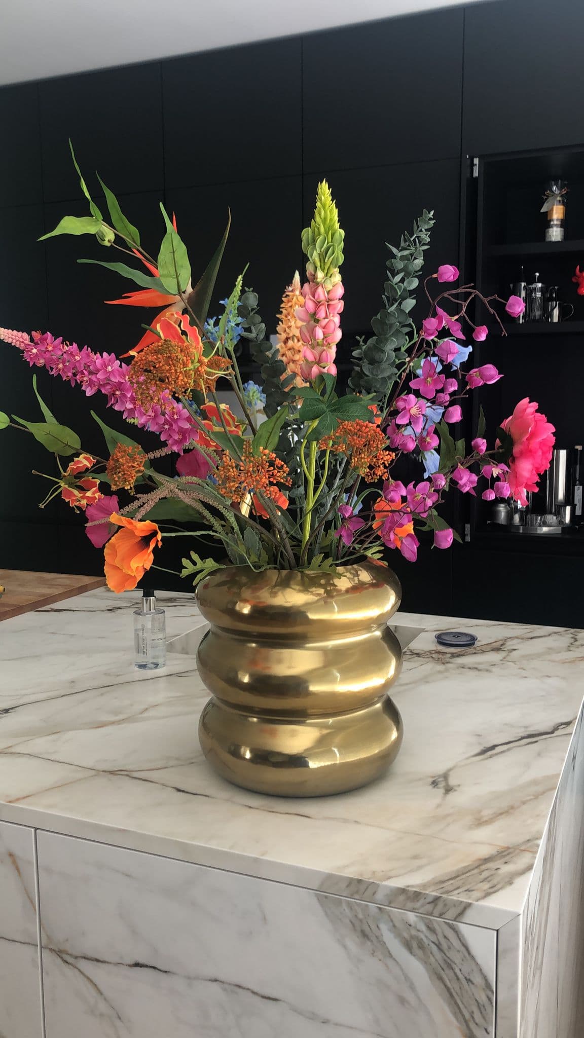 Kleurrijk boeket in een gouden geribbelde vaas op een marmeren keukeneiland